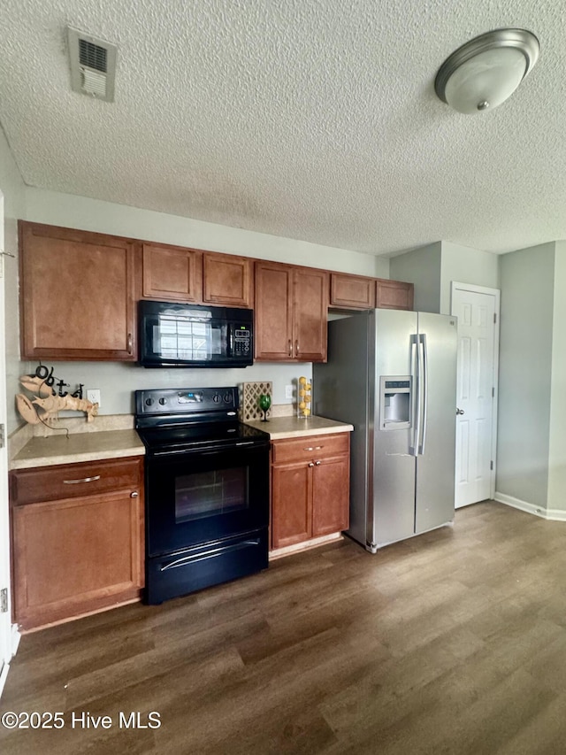 kitchen featuring a textured ceiling, visible vents, dark wood-type flooring, black appliances, and light countertops