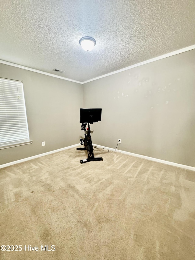 exercise room featuring a textured ceiling, baseboards, carpet flooring, visible vents, and crown molding