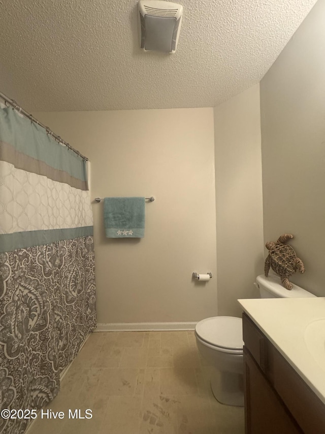 bathroom with curtained shower, vanity, toilet, and a textured ceiling
