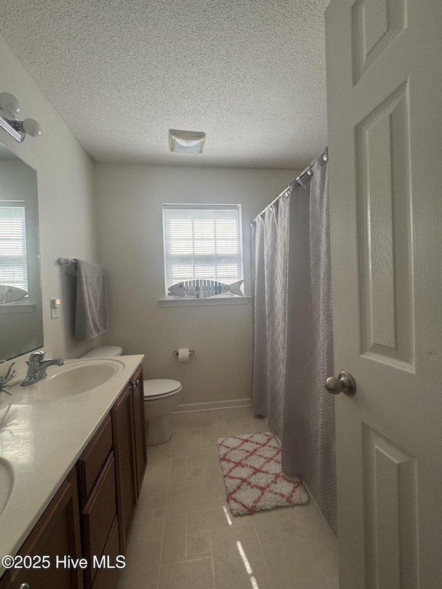 full bathroom featuring a textured ceiling, a healthy amount of sunlight, and a sink