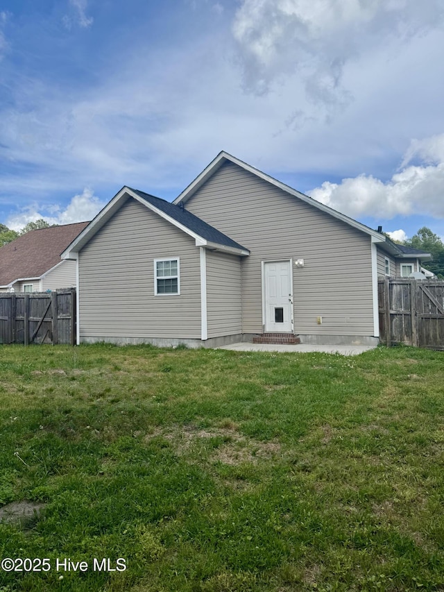 rear view of property featuring a lawn and a fenced backyard