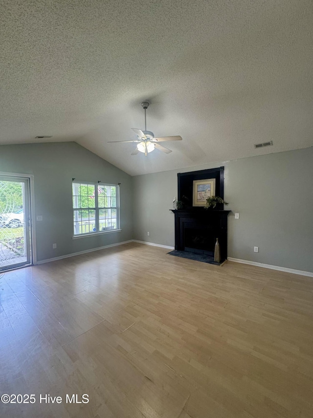 unfurnished living room featuring a ceiling fan, baseboards, light wood finished floors, and a textured ceiling