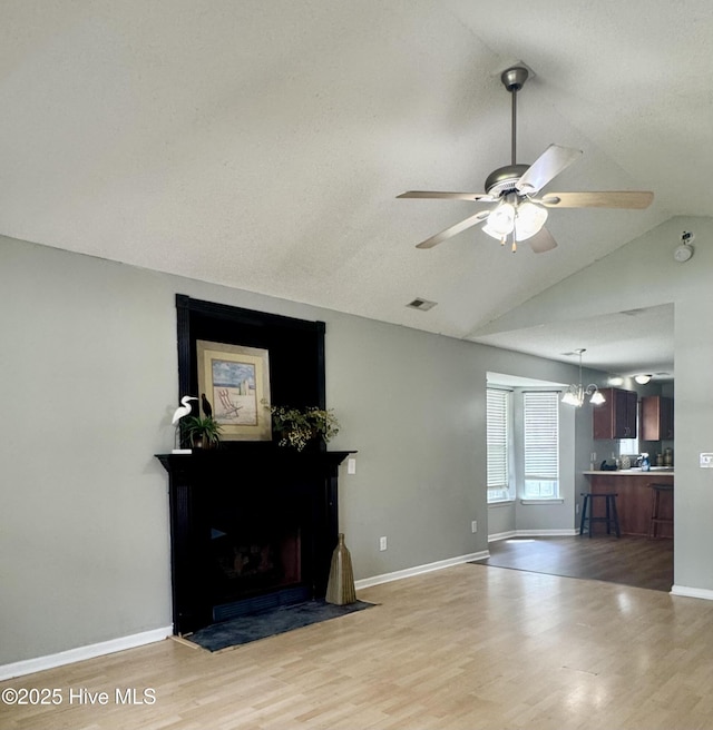 living room featuring vaulted ceiling, ceiling fan, visible vents, and light wood-style floors