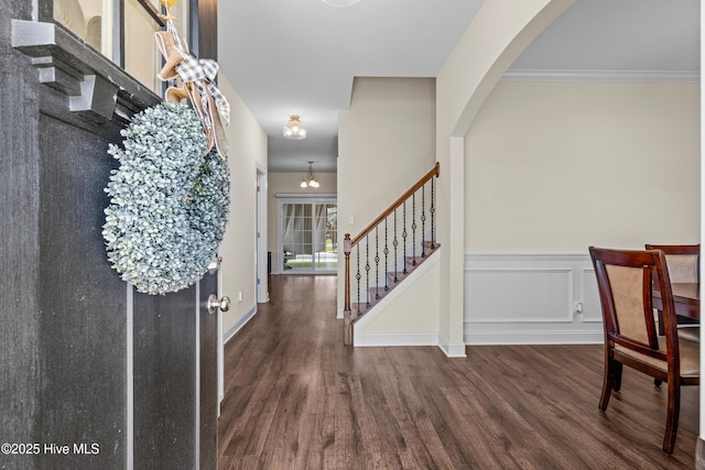 entryway featuring wainscoting, stairs, arched walkways, and wood finished floors