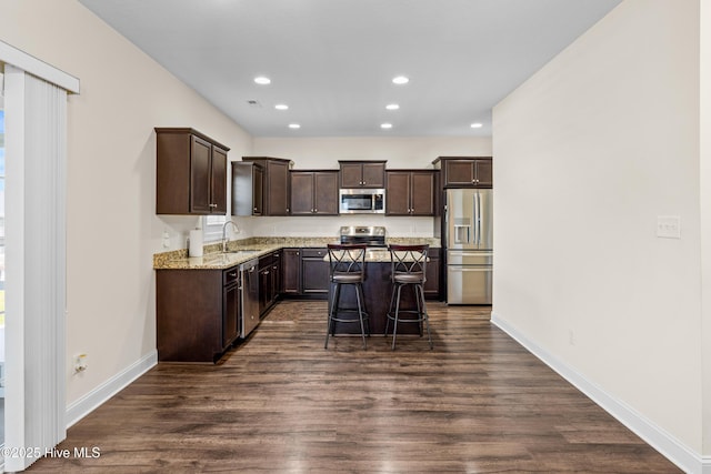 kitchen with a center island, dark brown cabinets, dark wood-style flooring, appliances with stainless steel finishes, and recessed lighting