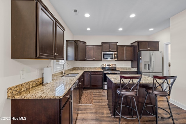 kitchen featuring dark brown cabinets, a sink, visible vents, dark wood-type flooring, and appliances with stainless steel finishes