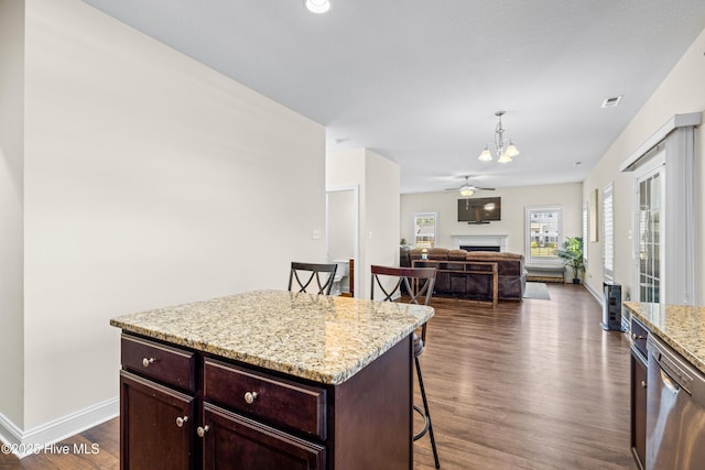kitchen featuring a breakfast bar area, stainless steel dishwasher, a chandelier, dark wood-type flooring, and a fireplace