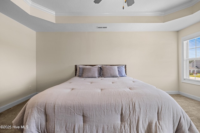 carpeted bedroom with baseboards, a raised ceiling, visible vents, and crown molding