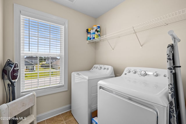 clothes washing area with a wealth of natural light, separate washer and dryer, laundry area, and light tile patterned flooring