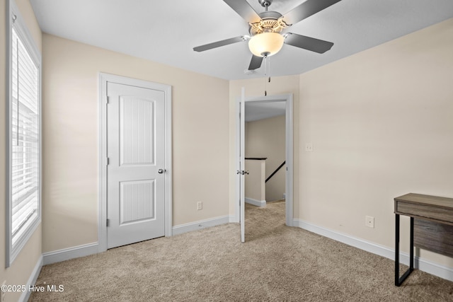 unfurnished bedroom with ceiling fan, carpet, and baseboards