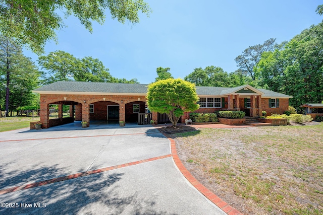ranch-style house with driveway, brick siding, and a front lawn