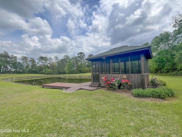 view of grassy yard with a water view and a sunroom
