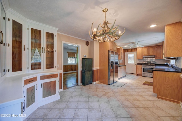 kitchen with appliances with stainless steel finishes, under cabinet range hood, a sink, a chandelier, and healthy amount of natural light
