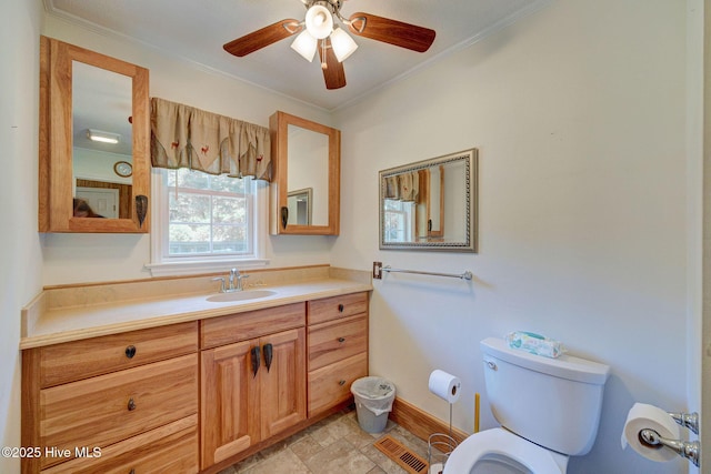 bathroom with toilet, crown molding, baseboards, a ceiling fan, and vanity
