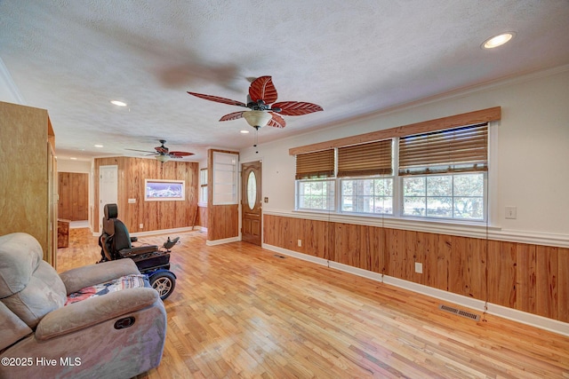 living area featuring wooden walls, a textured ceiling, light wood-style floors, recessed lighting, and ceiling fan