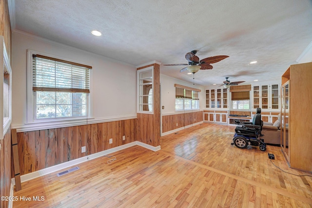 living room with a textured ceiling, wood finished floors, a wainscoted wall, baseboards, and recessed lighting