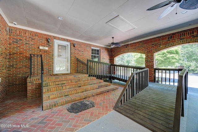 entrance to property featuring a ceiling fan, brick siding, and a surveillance system