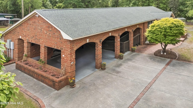 view of front of home with brick siding, a shingled roof, and driveway