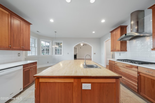 kitchen with wall chimney exhaust hood, a sink, white dishwasher, gas cooktop, and light countertops