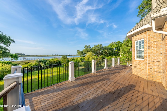 wooden deck with a water view and a lawn
