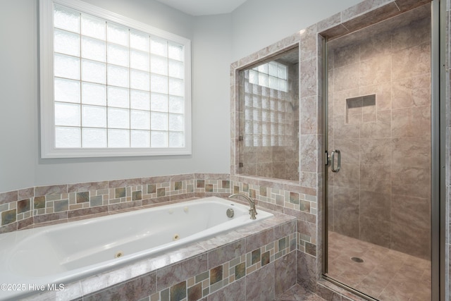full bathroom featuring plenty of natural light, a tub with jets, and a stall shower