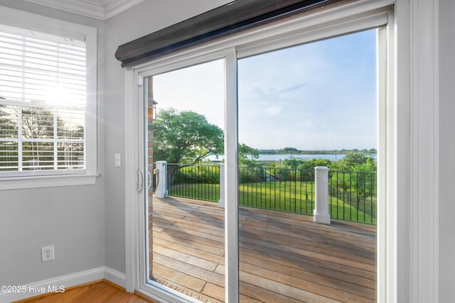 doorway with a water view, baseboards, wood finished floors, and ornamental molding