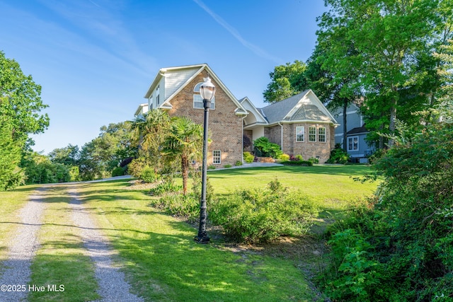 view of front facade featuring brick siding, a front yard, and driveway