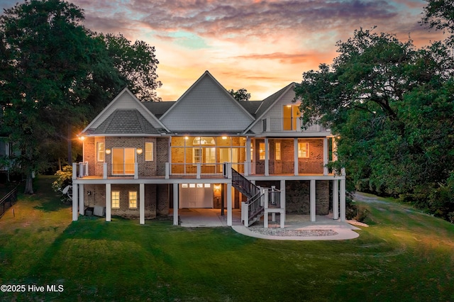 back of house featuring a patio, brick siding, a yard, stairs, and a balcony