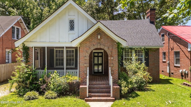 711 Kenan St W, Wilson, NC 27893 - tudor house with a shingled roof, brick siding, board and batten siding, a chimney, and a porch