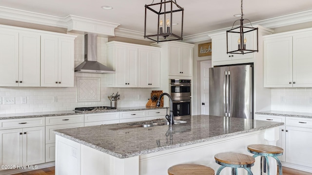 216 National Dr, Pinehurst, NC 28374 - kitchen featuring wall chimney range hood, appliances with stainless steel finishes, a sink, decorative backsplash, and white cabinetry