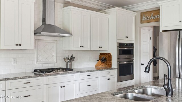 216 National Dr, Pinehurst, NC 28374 - kitchen featuring wall chimney range hood, a sink, stainless steel appliances, white cabinets, and ornamental molding