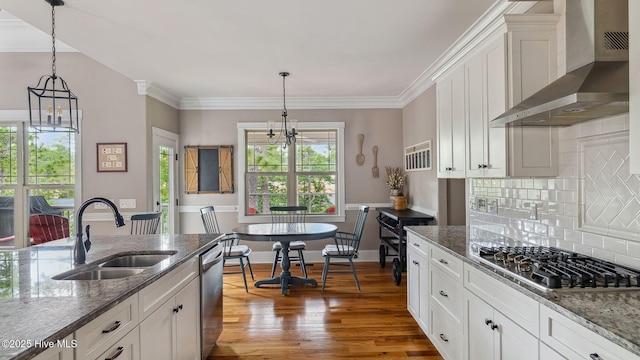 216 National Dr, Pinehurst, NC 28374 - kitchen with wall chimney range hood, a sink, a chandelier, appliances with stainless steel finishes, and decorative backsplash
