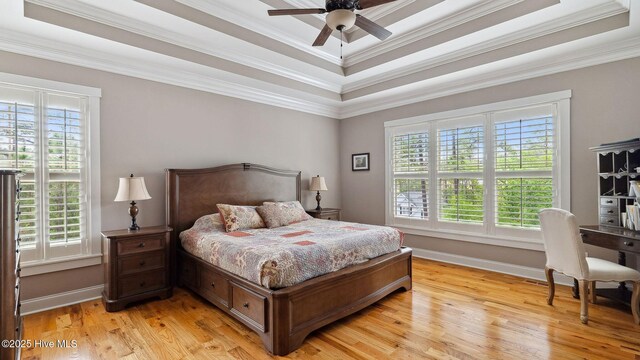 216 National Dr, Pinehurst, NC 28374 - bedroom featuring multiple windows, a tray ceiling, crown molding, light wood-type flooring, and baseboards