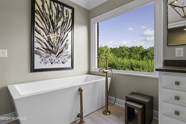 390 Whitebridge Rd, Hampstead, NC 28443 - bathroom with baseboards, vanity, a freestanding bath, and wood finished floors