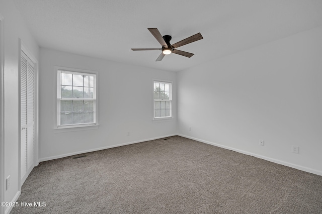 empty room with plenty of natural light, carpet floors, and ceiling fan