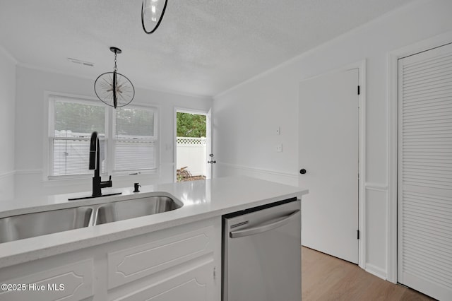 kitchen featuring dishwasher, a sink, light countertops, a textured ceiling, and light wood-style floors