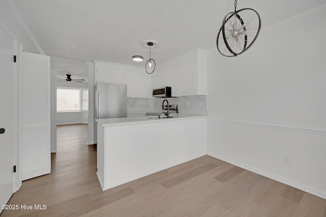 kitchen with light wood-style flooring, light countertops, white cabinets, a ceiling fan, and a peninsula