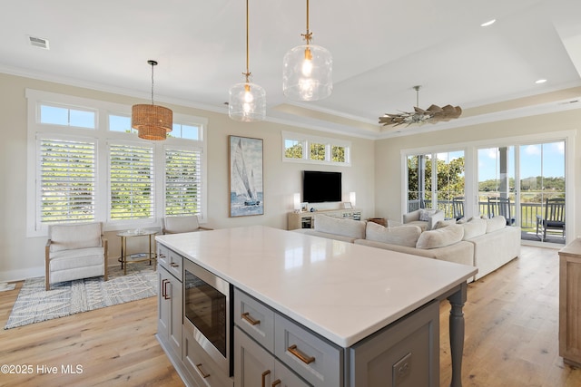 1063 Tide Ridge Dr, Supply, NC 28462 - kitchen with stainless steel microwave, gray cabinetry, light wood-style floors, crown molding, and light countertops