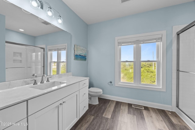 bathroom featuring a shower stall, baseboards, wood finished floors, and vanity