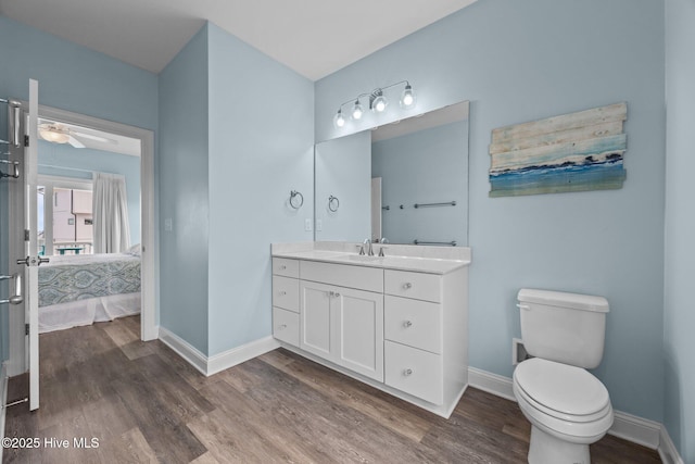 bathroom with ensuite bathroom, baseboards, wood finished floors, and toilet