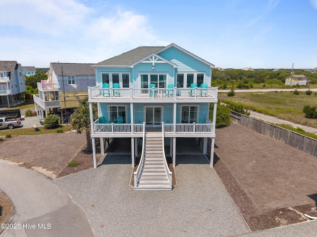 beach home with a carport, driveway, stairs, and a balcony