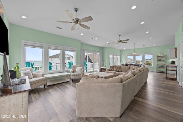 living area with a ceiling fan, plenty of natural light, dark wood-type flooring, and recessed lighting