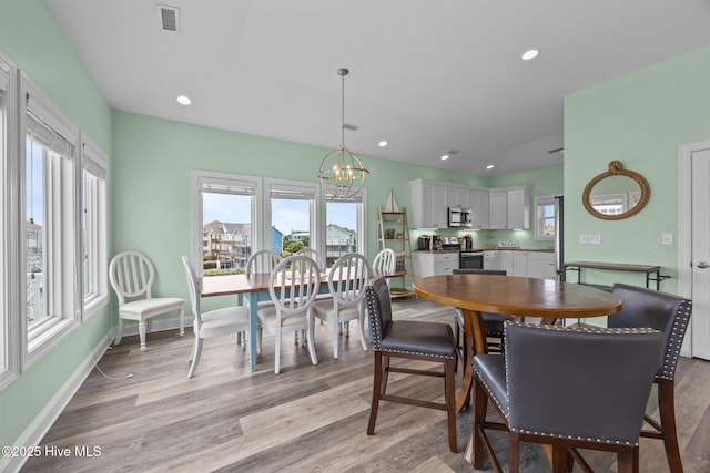 dining space featuring a chandelier, light wood finished floors, baseboards, and recessed lighting