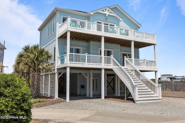 coastal home with a carport, driveway, a balcony, and stairs