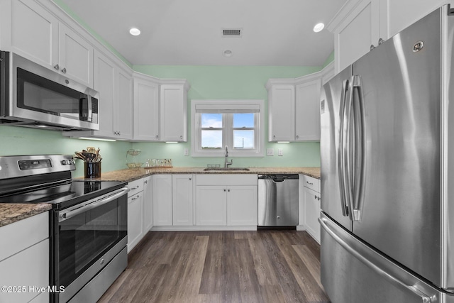 kitchen featuring stainless steel appliances, a sink, white cabinetry, dark wood-style flooring, and recessed lighting