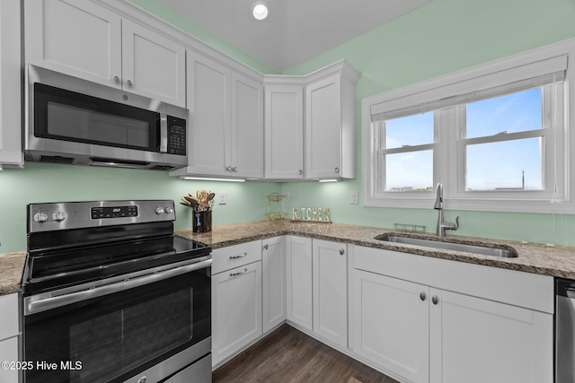 kitchen with appliances with stainless steel finishes, a sink, white cabinetry, and light stone countertops