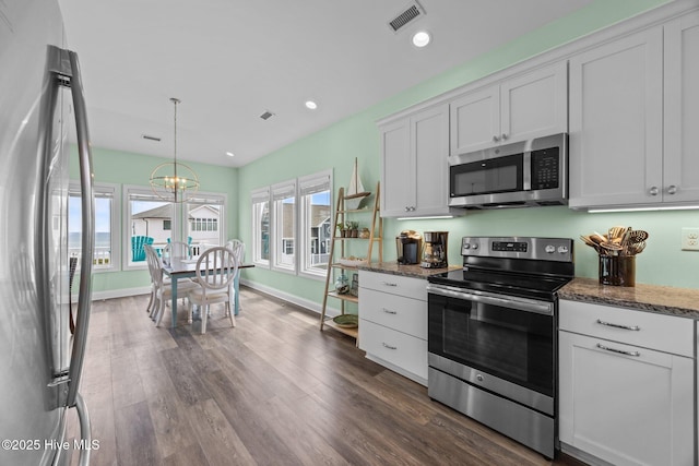 kitchen featuring stainless steel appliances, white cabinetry, dark wood-style flooring, dark stone countertops, and decorative light fixtures