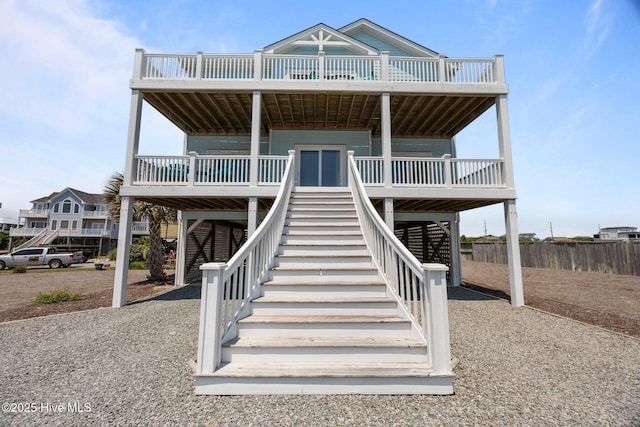 view of front of house with stairway, a deck, and fence