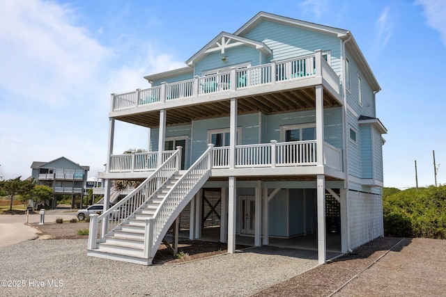 raised beach house featuring a carport, gravel driveway, and a porch