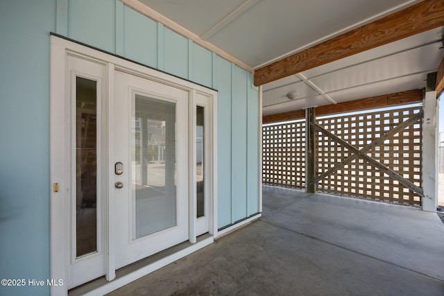 view of exterior entry with board and batten siding and a patio area
